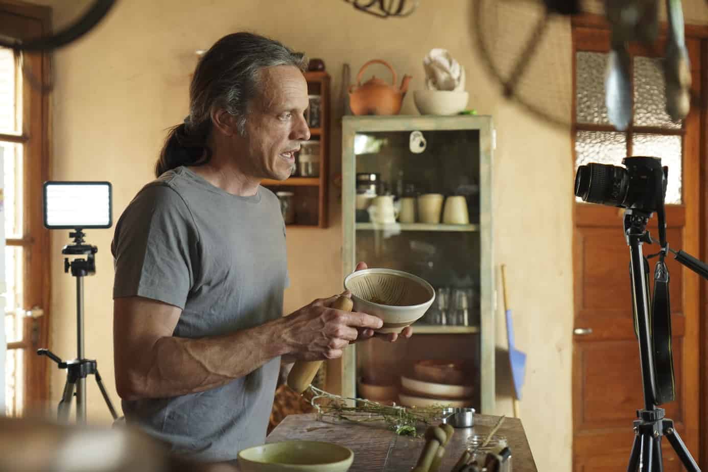 Hombre preparando comida saludable en un ambiente natural y acogedor.