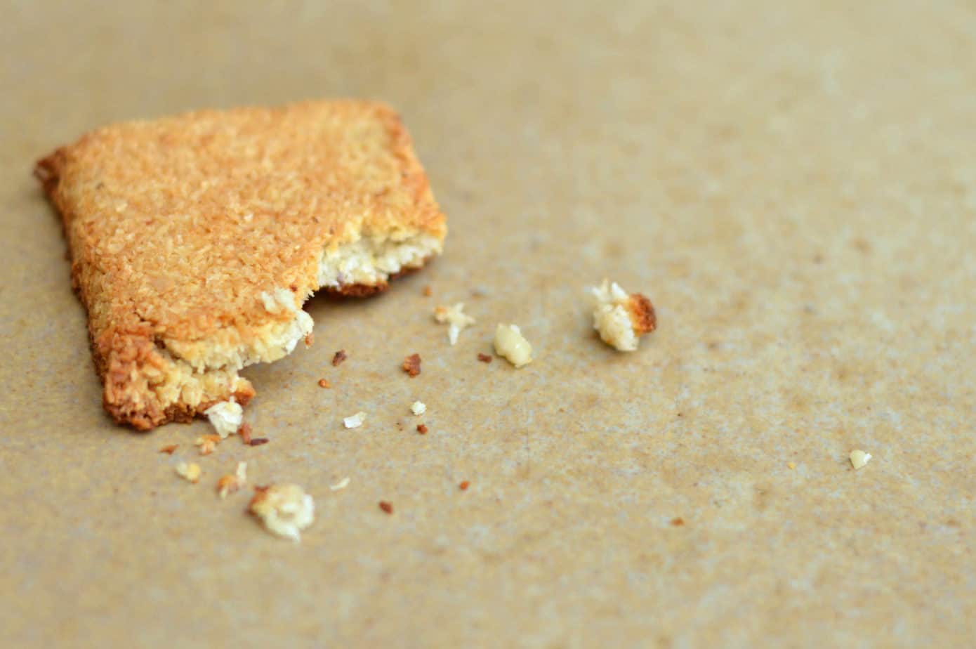 Trozo de galleta con migajas sobre papel kraft, concepto de alimentación consciente.