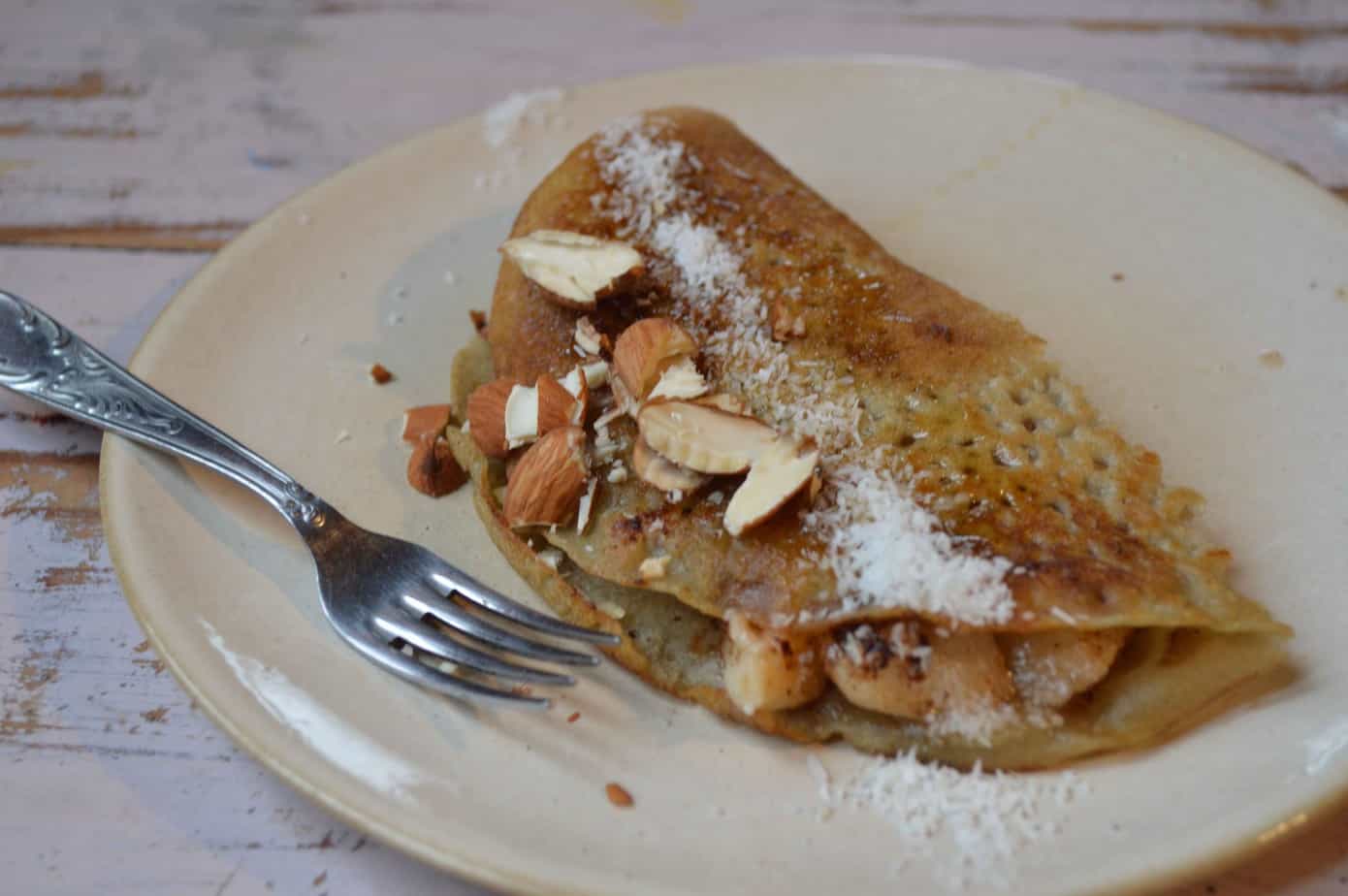 Crepa rellena con almendras y azúcar, presentada en plato de cerámica.