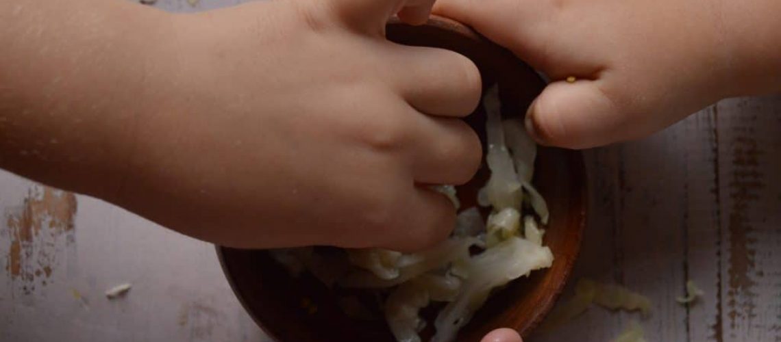 Niños comiendo chucrut, vista de las manos